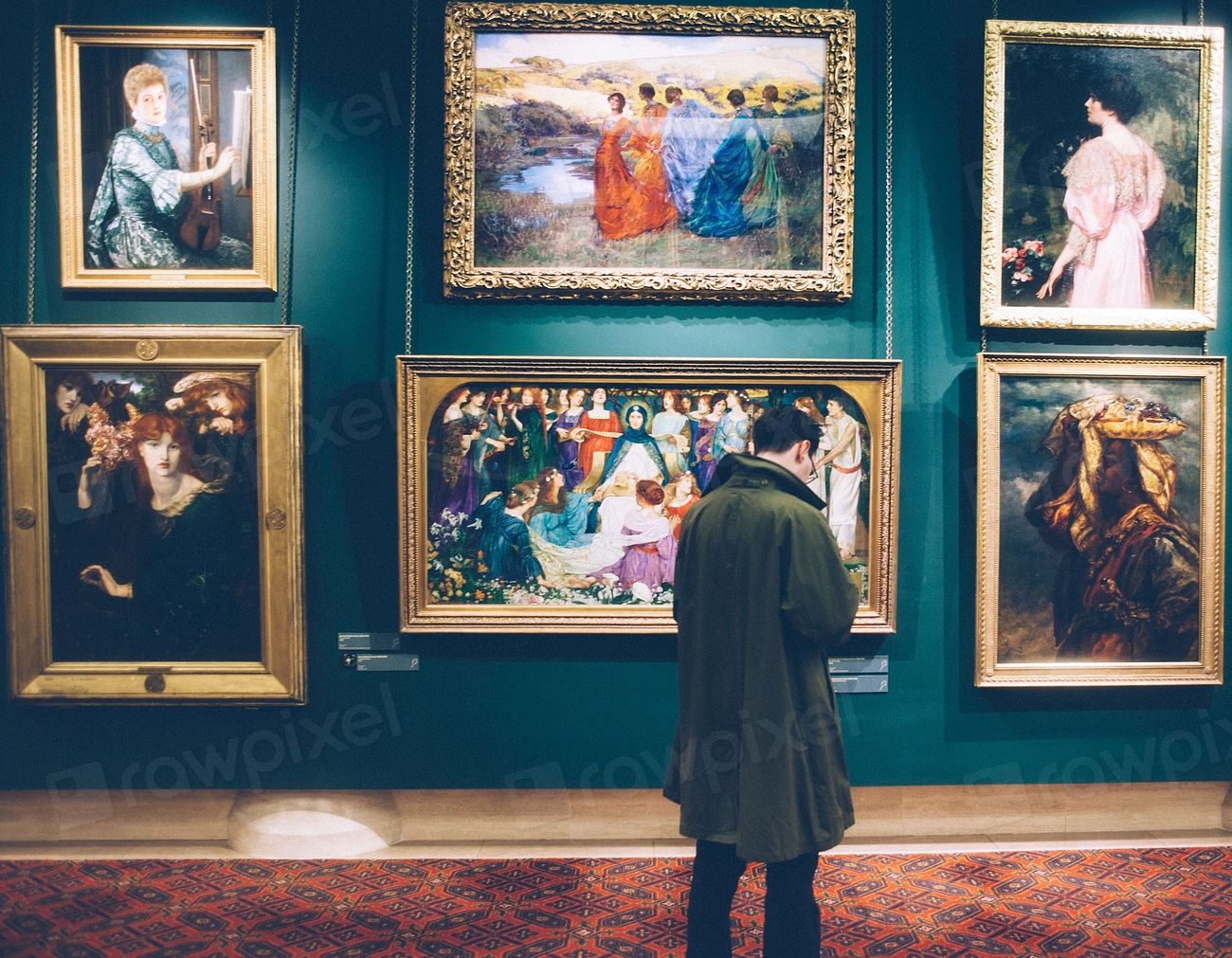 A visitor standing before framed paintings in a gallery