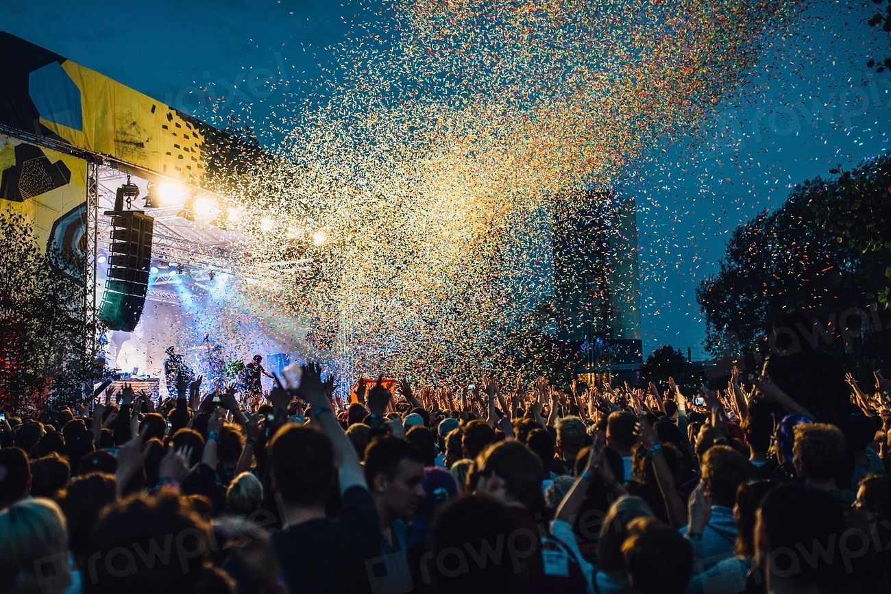 Confetti bursting over a festival crowd at dusk